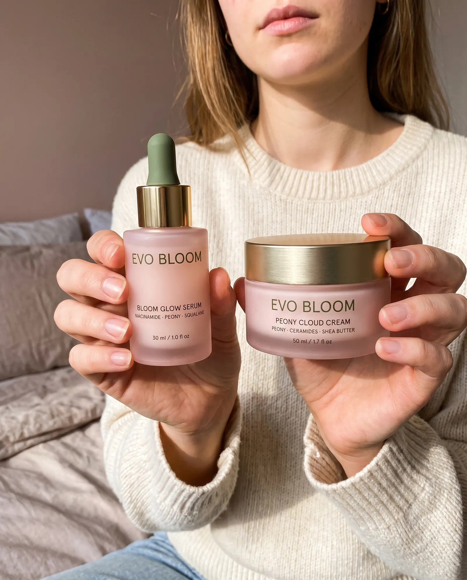 Two hands held out toward the camera holding Bloom Glow Serum and a jar of Peony Cloud Cream